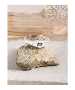 Close-up of S925 silver irregular ring with purple zircon on a natural stone base