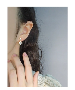 Détail macro de boucles d'oreilles cœur en zircon doré portées avec pierres brillantes