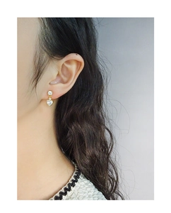Gros plan d'élégantes boucles d'oreilles cœur en or et zircon portées sur l'oreille