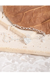 Detailed view of S925 sterling silver heart bracelet on stone surface with water ripple
