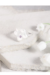 Detail of silver flower ring featuring a purple zircon center and adjustable open band