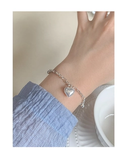 Close-up of a polished S925 silver heart charm bracelet worn on a female wrist