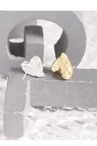 Macro shot of asymmetric melting heart earrings with textured silver and gold finish