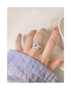 Detailed view of silver flower ring with purple zircon worn by a model in soft lighting