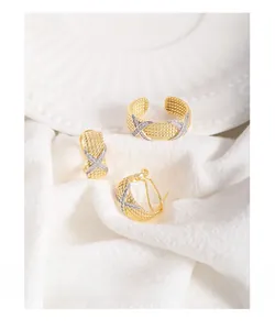 Close-up of gold twist texture earrings and ring with silver cubic zirconia cross detail