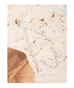 Macro detail of S925 sterling silver heart bracelet on natural stone with dry leaves