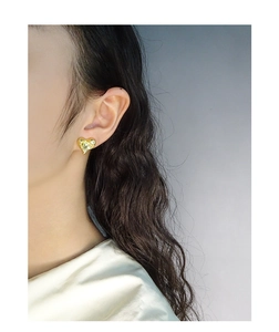 Detailed view of a gold heart stud earring with unique melted ripple texture on model