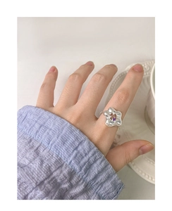 Detailed close-up of a silver floral zircon ring on finger with purple center stone