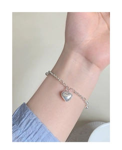 Detailed close-up of a sterling silver heart pendant bracelet on a woman wrist