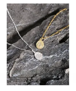 Detail of irregular textured coin pendants on Figaro chains in gold and silver S925