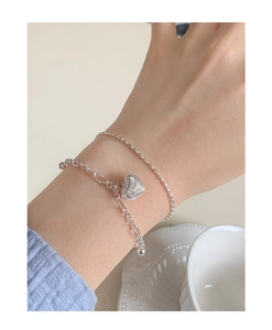 Detail of double-layer silver heart bracelet with 3D pendant on a female wrist