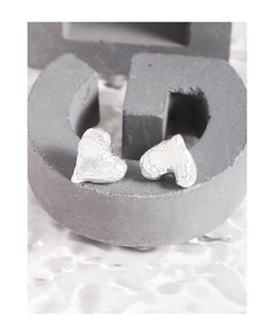 Detailed macro view of silver heart earrings with unique melted lava textured surface
