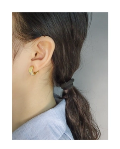 Detail of gold C-shaped twisted earrings with micro-set zircon on model's ear