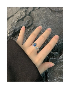 Detail eines S925 Silberrings mit blauem Opal und 3D-Bär auf grauem Felsen-Hintergrund