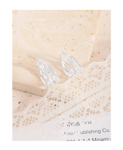 Macro view of S925 sterling silver knotted earrings on marble and lace background