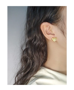 Detailed close-up of golden heart earrings with a unique textured hammered finish