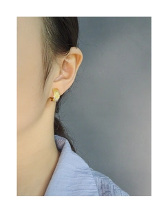 Close-up of gold lattice woven hoop earrings with cubic zirconia on model ear