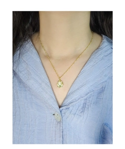 Detail of a gold Figaro chain necklace with an irregular textured oval pendant on model
