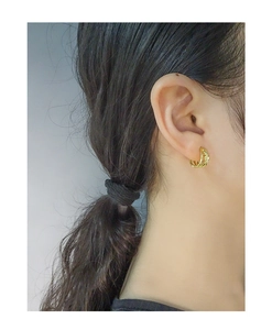 Close-up of triple-layered golden twisted hoop earrings worn on a female model