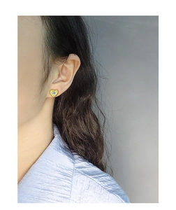 Détail de boucles d'oreilles cœur en argent S925 avec zircon bleu et texture vintage sur l'oreille