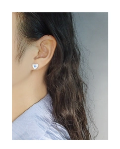 Détail de puce d'oreille cœur en argent avec zircon bleu et texture radiale sur l'oreille
