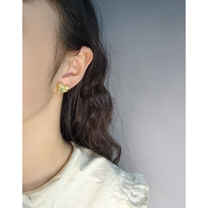 Minimalist gold heart earrings with molten lava texture shown on model in a side view