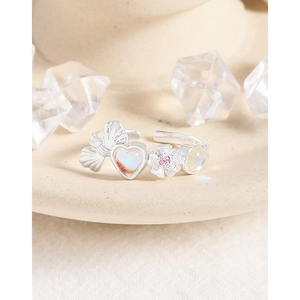 S925 silver bow and heart moonstone ring with pink gemstone flower on beige background