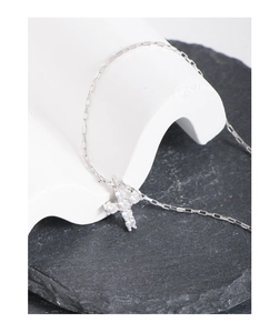 Macro detail of silver cross pendant with sparkling zircons on a textured black stone base