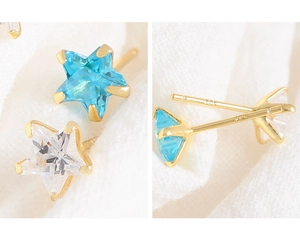 Close-up of 14K gold star earrings with blue and clear zircon in prong setting