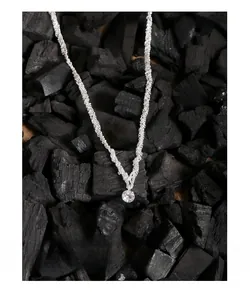 Vue macro d'un collier en argent avec pendentif zircon rond brillant sur charbon