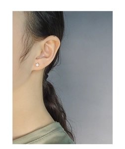 Close-up of minimalist gold star stud earrings with zircon stone worn on an ear