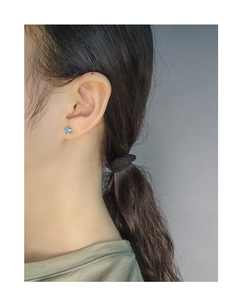 Close-up of minimalist blue star-shaped zircon stud earrings worn on female ear