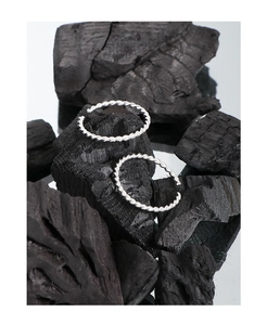 Detailed macro view of S925 sterling silver twist rings on a textured dark background