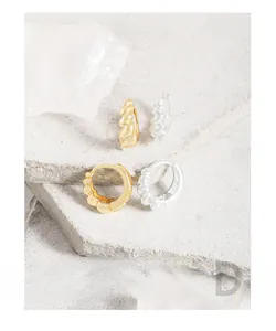 Detail of twisted croissant-style hoop earrings in S925 silver and 18K gold finish