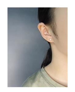 Close-up of minimalist gold star stud earrings with micro-set zircons on a model