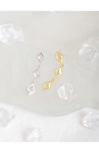 Macro detail of triple rhombus geometric drop earrings in gold and silver finish
