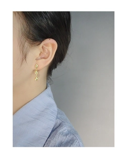 Close-up of elegant gold triple rhombus drop earrings worn to show the vertical drape