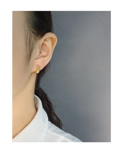 Detailed close-up of golden croissant-style textured hoop earrings on a female model