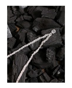 Gros plan d'un collier en argent avec zircon sur charbon noir, détails de la chaîne