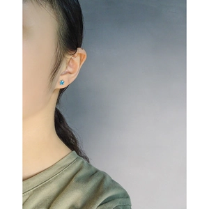 Elegant gold S925 sterling silver mini star stud earrings with blue zircon on model