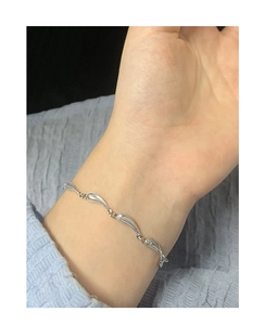 Close-up of S925 sterling silver wave link bracelet on female wrist with polished finish