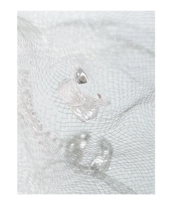 Close-up of S925 silver ear cuff with irregular lava texture on metallic mesh background