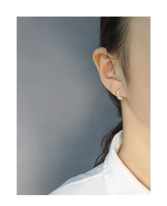 Detail view of S925 silver croissant hoop earrings with twisted texture on a model's ear
