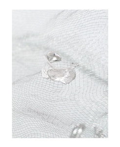 Macro shot of silver irregular textured ear cuff on industrial metal mesh background