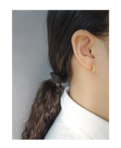 Macro detail of golden croissant twist hoop earrings worn by model for elegant styling