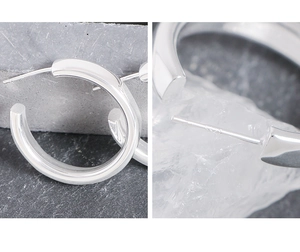 Détail du poinçon S925 sur les boucles d'oreilles courbées polies au design épuré