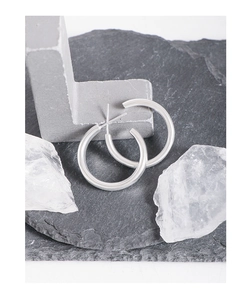Gros plan de boucles d'oreilles créoles polies en argent S925 sur fond de pierre