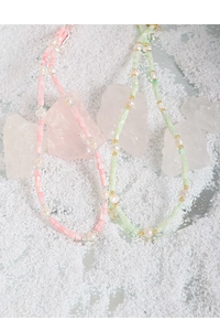 Detail of baroque pearl necklaces with pink and green beads on a mineral stone background