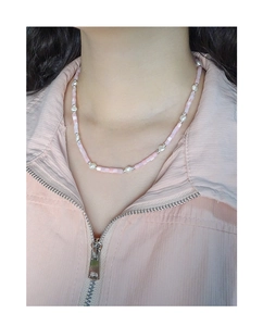 Detail of beaded necklace featuring pink shell beads and white baroque pearls on model