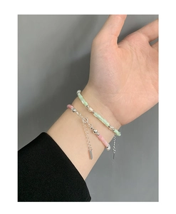 Close-up of pink and green beaded bracelets with S925 silver charms on a model wrist